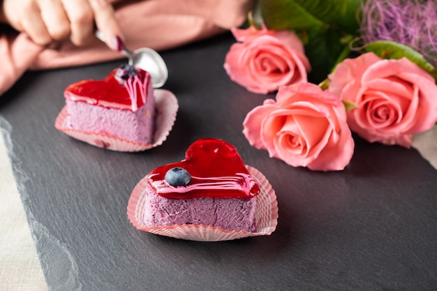 Woman eating heart shaped dessert on a slate board with roses on a romantic evening