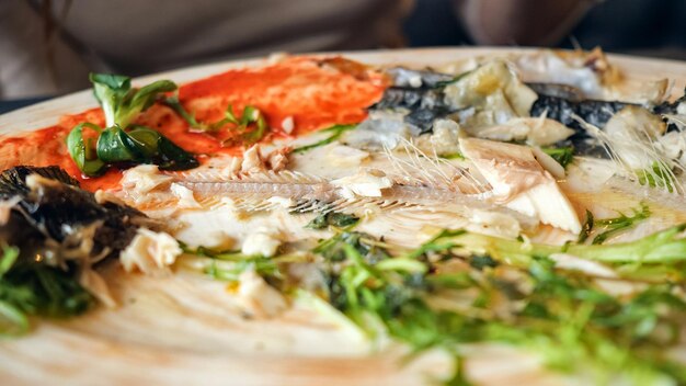 Woman eating leftovers fish with knife and fork in cafe, close up