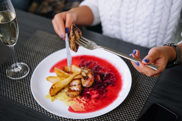 Woman eating meat and drink champagne in a restaurant