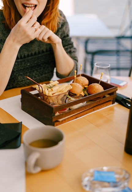 Woman eating mini burgers and fries