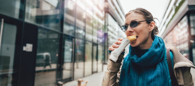 Photo woman eating sandwich and walking