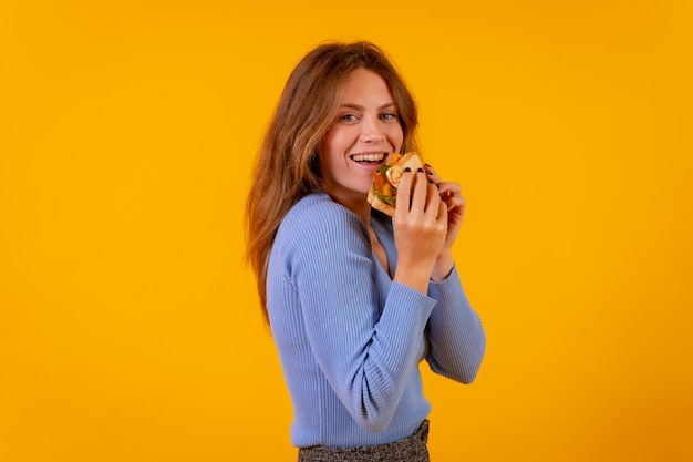 Woman eating a sandwich on a yellow background healthy and vegetarian food