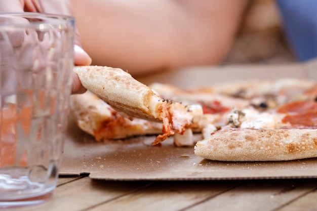 Woman eating tasty pizza outdoor in street cafe Fast food takeaway in sunny day