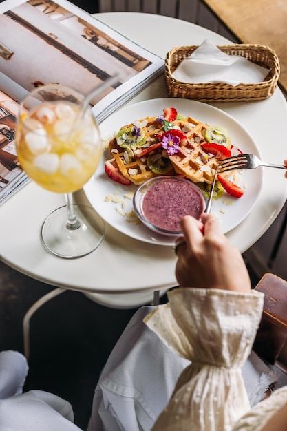 woman eating waffles with strawberries and fruits