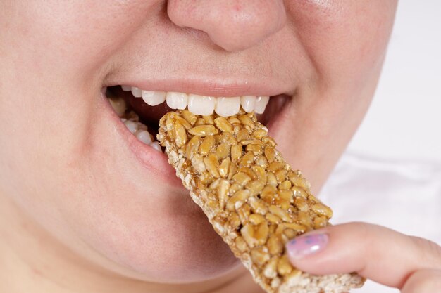 A woman eats a stick of sunflower seeds sweet dessert