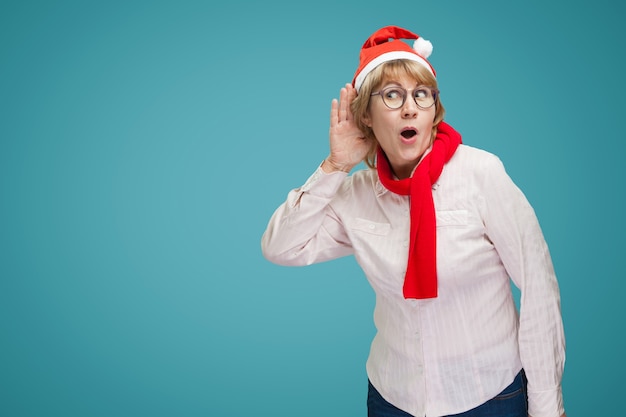 Woman eavesdropping. A middle-aged woman in the new year and Christmas clothes on a blue background