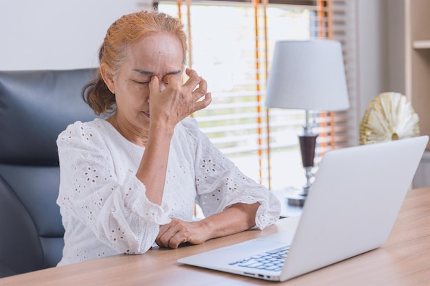 Woman elderly eyes pain from Asthenopia stress tired sinus suffer fatigue from hard work with computer screen