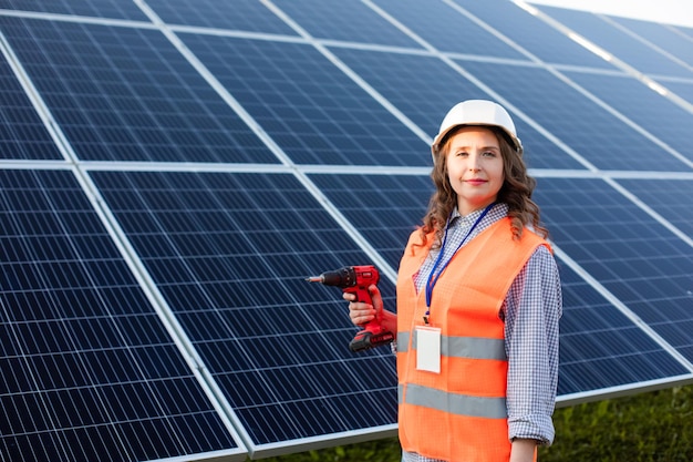 The woman electrician with screwdriver at the solar station