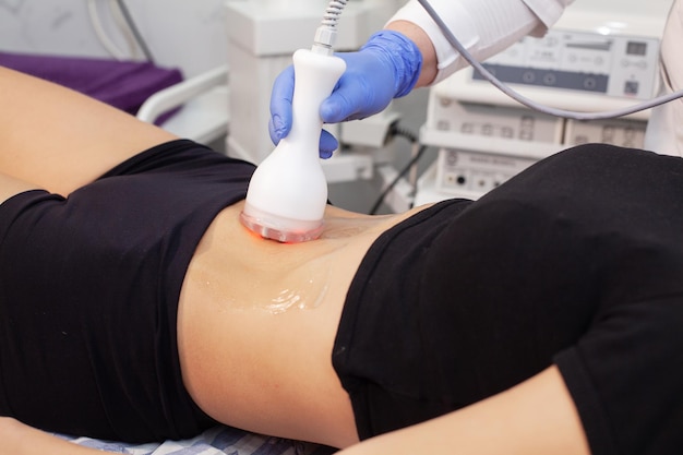 Woman at electro stimulation therapy in cosmetic clinic