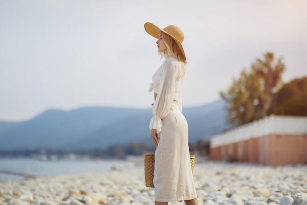 Woman in elegant beach outfit outdoors against palm trees on the background during summer