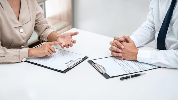 Woman employer is asking with candidate question and explaining about job description to applicant while sitting to job interview in office