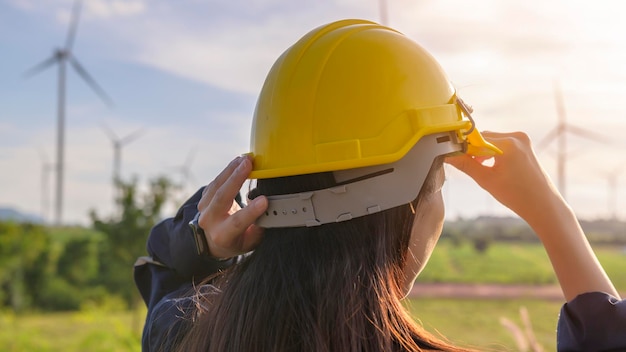 A woman engineer is putting a protective helmet on her head at sunset