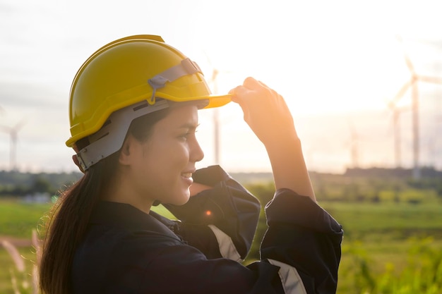 A woman engineer is putting a protective helmet on her head at sunset