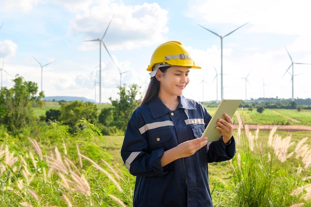 A woman engineer is wearing a protective helmet on her head using tablet