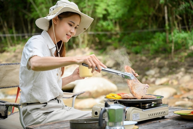 Woman enjoy camping at the campground roasted some porkchop making a steak