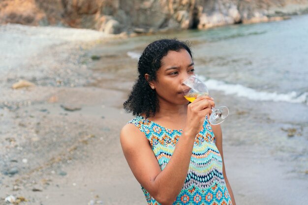 Woman enjoying a glass of wine by the sea.