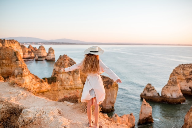 Woman enjoying great view on the rocky coastline during the sunrise in Lagos on the south of Portugal