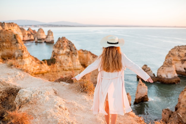 Woman enjoying great view on the rocky coastline during the sunrise in Lagos on the south of Portugal