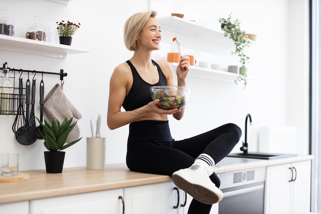 Photo woman enjoying healthy salad in modern kitchen