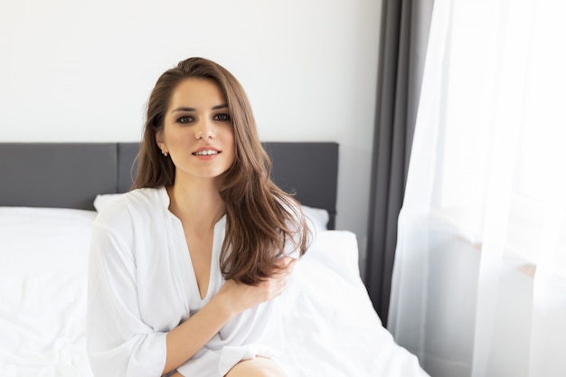 Woman enjoying morning awakening in a soft snow-white bed. 