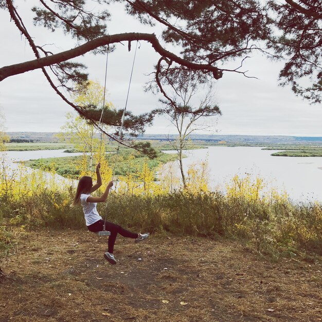 Photo woman enjoying on rope swing at field