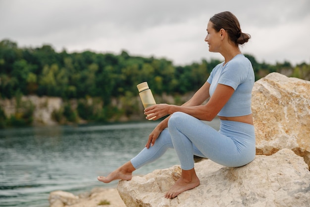 Photo a woman enjoying the serenity and calm by the scenic lake while dressed in activewear