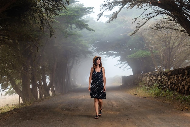 A woman enjoying walking through foggy trees towards the juniper forest in El Hierro Canary Islands