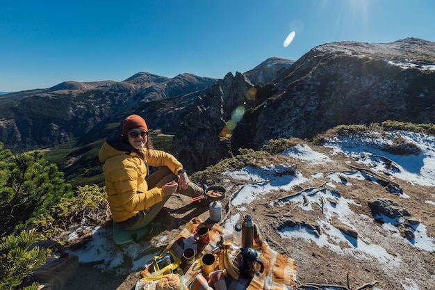 A woman enjoys a beautiful view of rocks and mountains while having a picnic with a tourist equip