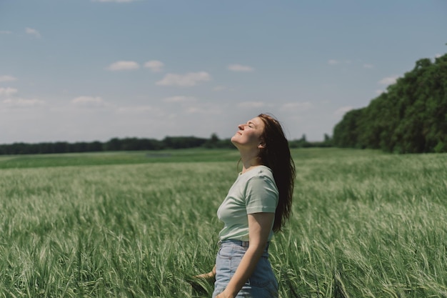 A woman enjoys the fresh air in nature in a green barley field Summer countryside and gathering flowers Atmospheric tranquil moment