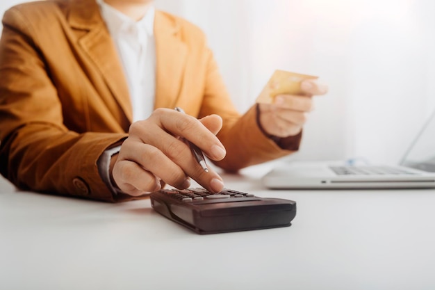 Woman entrepreneur using a calculator with a pen in her hand calculating financial expense at home office