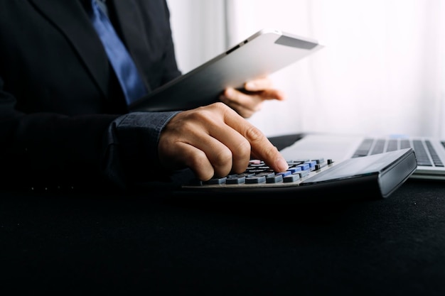 Woman entrepreneur using a calculator with a pen in her hand calculating financial expense at home office