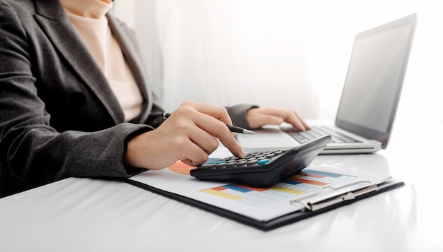 Woman entrepreneur using a calculator with a pen in her hand calculating financial expense at home office