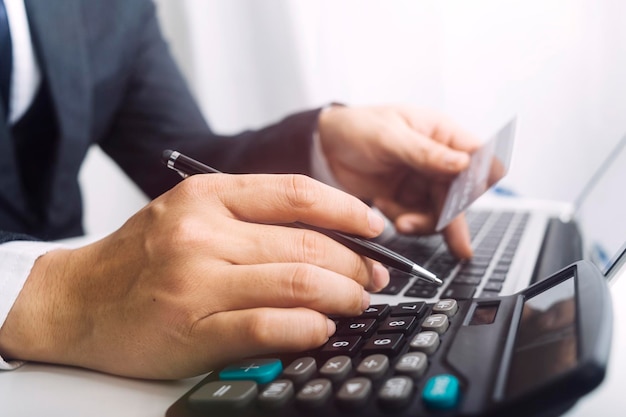 Woman entrepreneur using a calculator with a pen in her hand calculating financial expense at home office