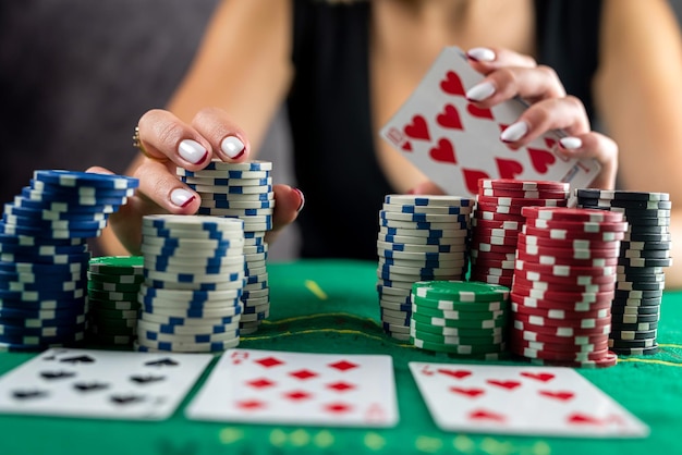 Woman in an evening black dress plays poker in casino wrapping all the winnings in her hands