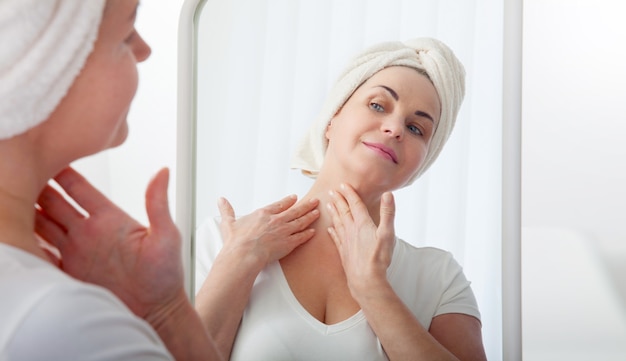 Woman examines herself for wrinkles in mirror