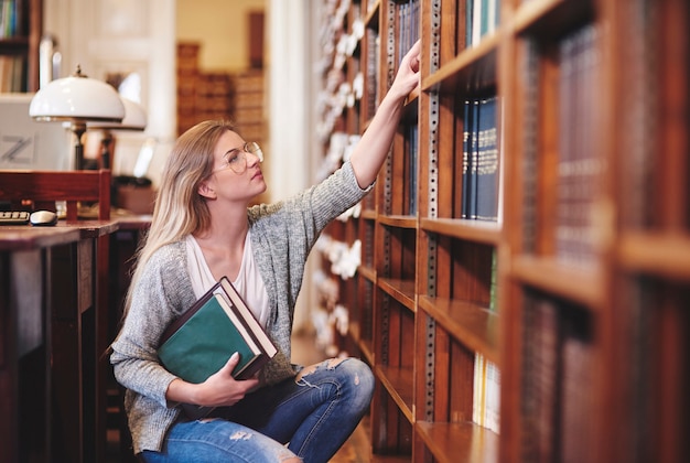 Woman examining books in library