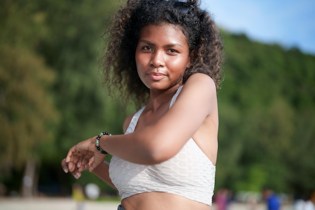 Woman exercises and stretches muscles before outdoor workout Portrait sexy Asian African lady preparing herself for fitness at beach