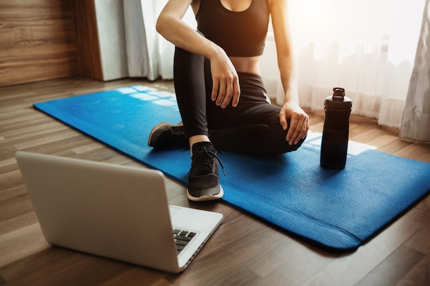 Woman exercising at home and watching training videos with dumbbells and looking at laptop. effect light