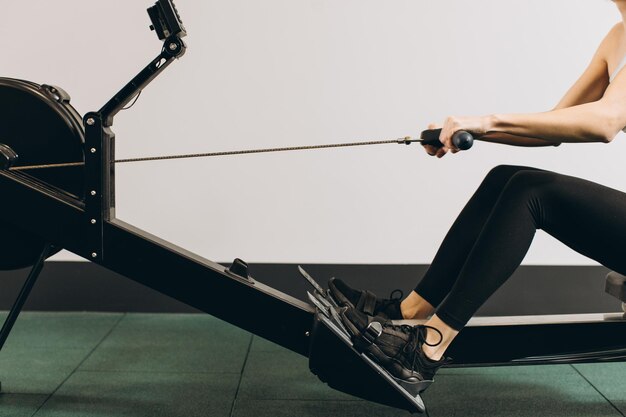 Photo woman exercising on rowing machine part of circuit training warmup cardio session