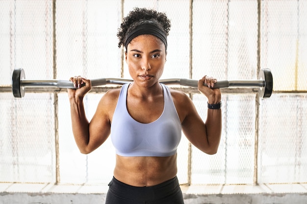 Woman exercising weighlifting with barbell at fitness gym