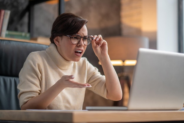 A woman in eyeglasses looking surprised and uncertain