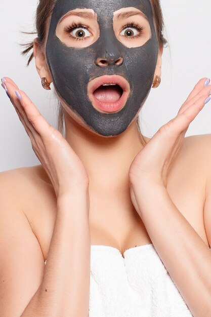 Woman Face Mask. Portrait Of Beautiful Girl Removing Cosmetic Black Peeling Mask From Facial Skin. Closeup Of Attractive Young Woman With Natural Makeup And Cosmetic Peel Mask On Face. High Resolution