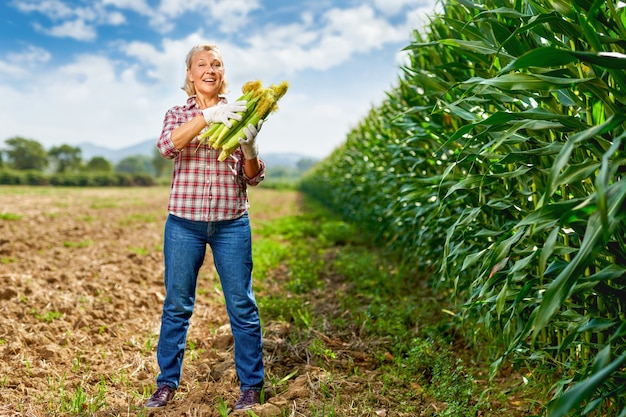 Woman farmer holding corn crop in her hands.