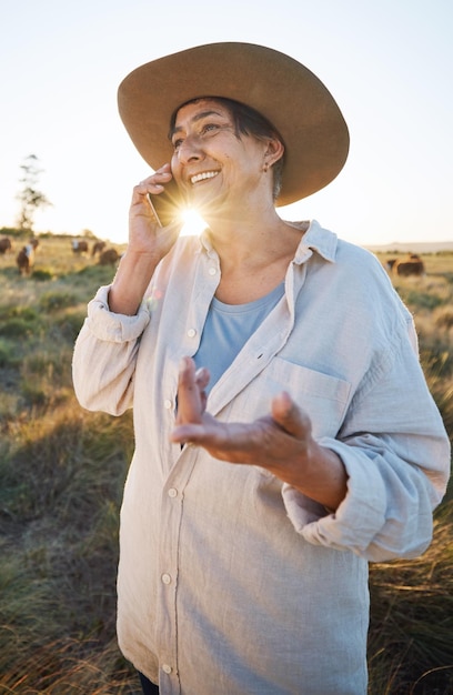 Woman farmer and phone call in morning countryside and person on farm with smile for live stock in nature with connection Happy female worker and social network communication and contact