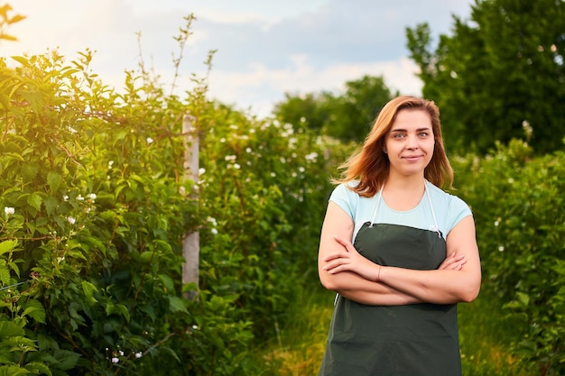 Woman farmer working in fruit garden Biologist inspector examines blackberry bushes