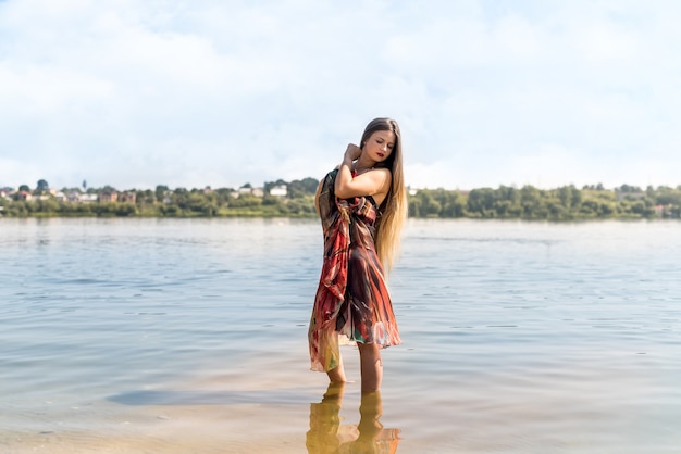 Woman in fashion dress posing on the ocean coast