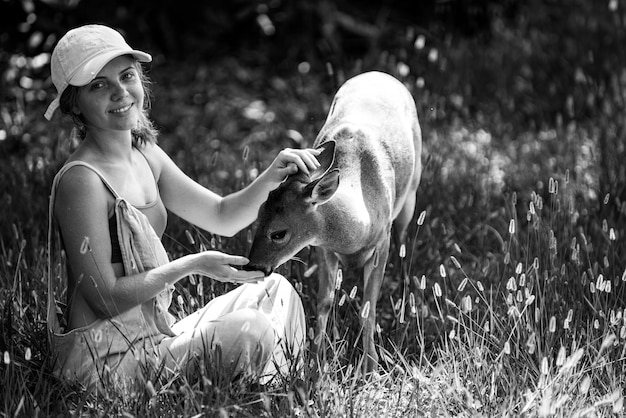 Woman feed bambi deer unity with nature wild animals concept girl feeding fawn animal at park