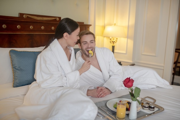 A woman feeding his partner with a piece of fruit