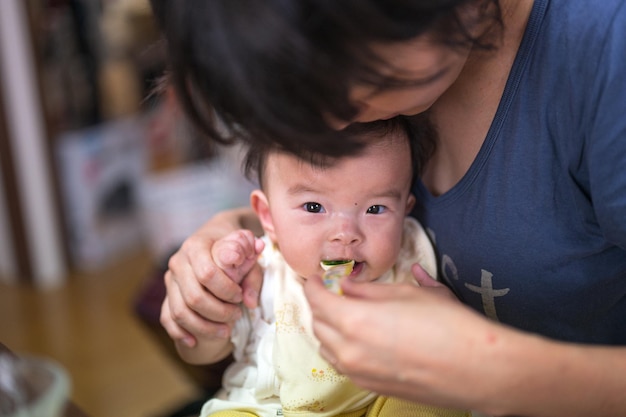 A woman feeds a baby with a blue shirt that says'love is in the air '