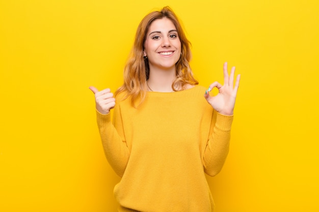 woman feeling happy, amazed, satisfied and surprised, showing okay and thumbs up gestures, smiling